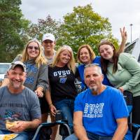 Attendees pose for a picture near truck in tailgate parking lot.